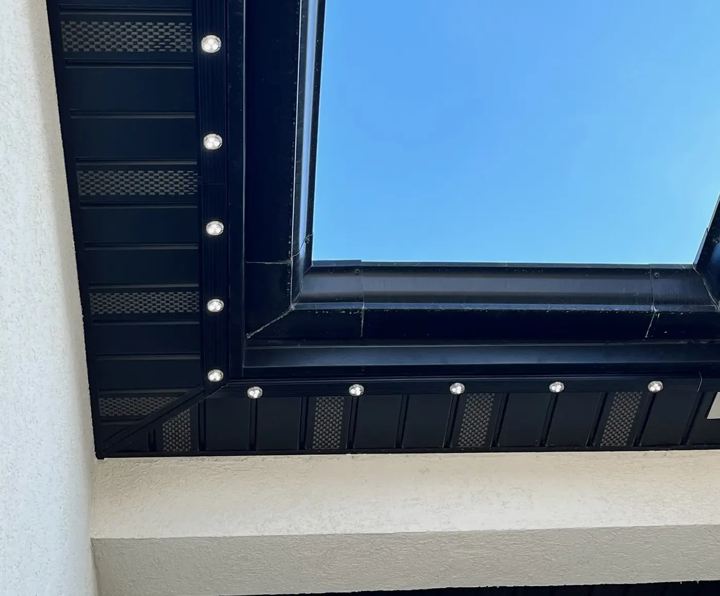 Daytime close-up of a slim black lighting channel against black trim