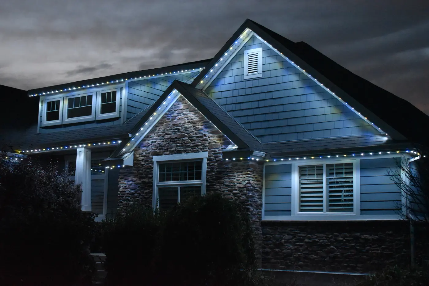 Craftsman home outlined in cool white and gold at night